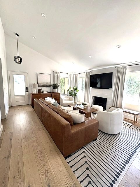 Long view of a living room with leather sofa, fireplace and patterned rug