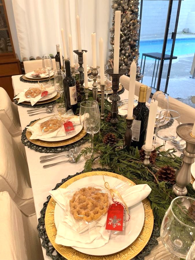Close-up of a holiday place setting with a wrapped treat, red tag and pewter candlesticks