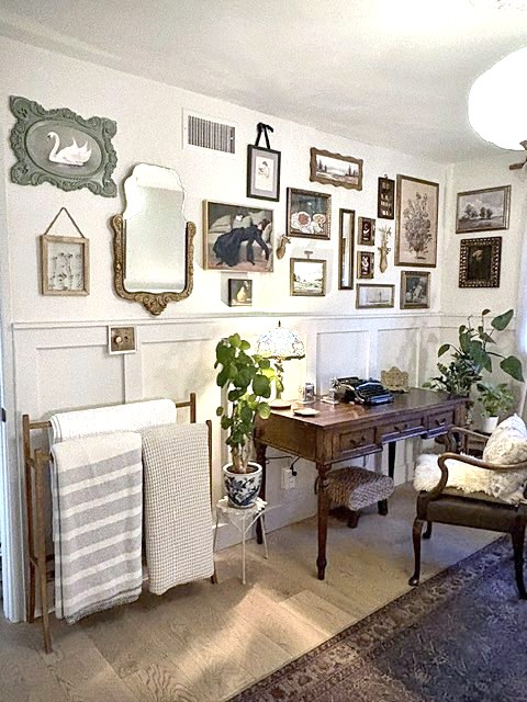 Writing corner with antique desk, plants and a framed gallery wall