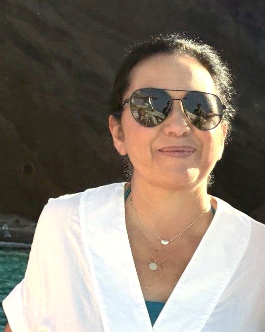 Dahlia, founder of DahlHouse, smiling in a white linen dress on a boat