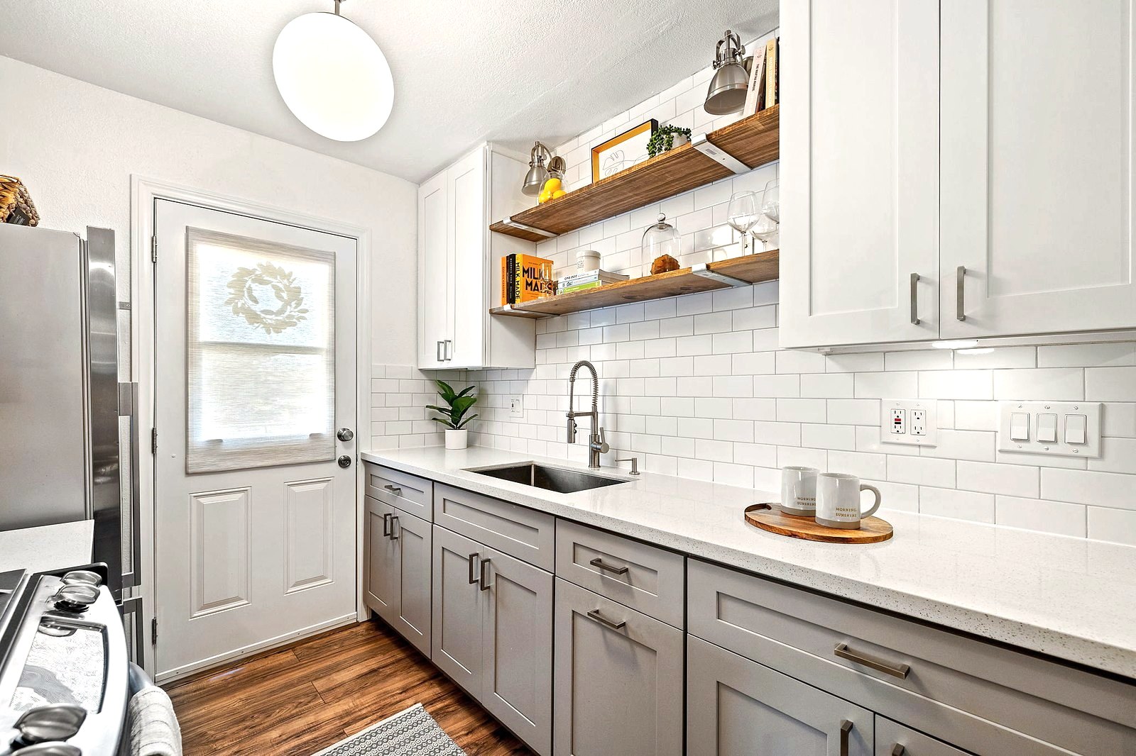 White kitchen with subway tile, open walnut shelves and styled counters