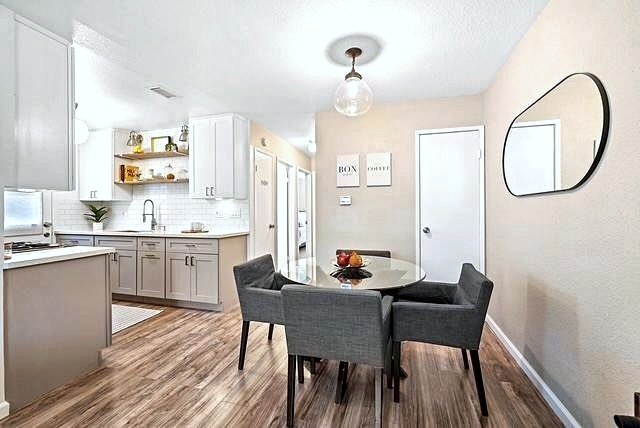 Dining area with round table, charcoal chairs and open kitchen beyond