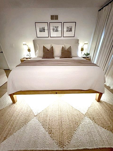 Primary bedroom with glowing under-bed light and woven diamond rug