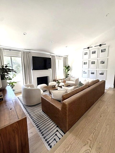 Bright living room with leather sofa, boucle chairs and a framed gallery wall