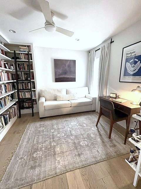 Reading den with bookshelves, cream sofa, desk and ceiling fan