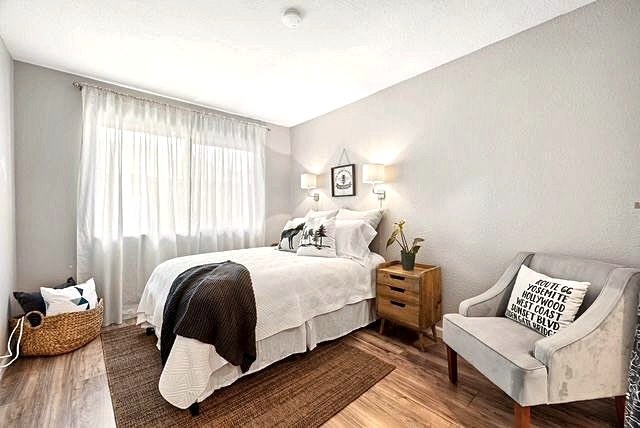 Guest bedroom with brown throw, nightstand and accent chair