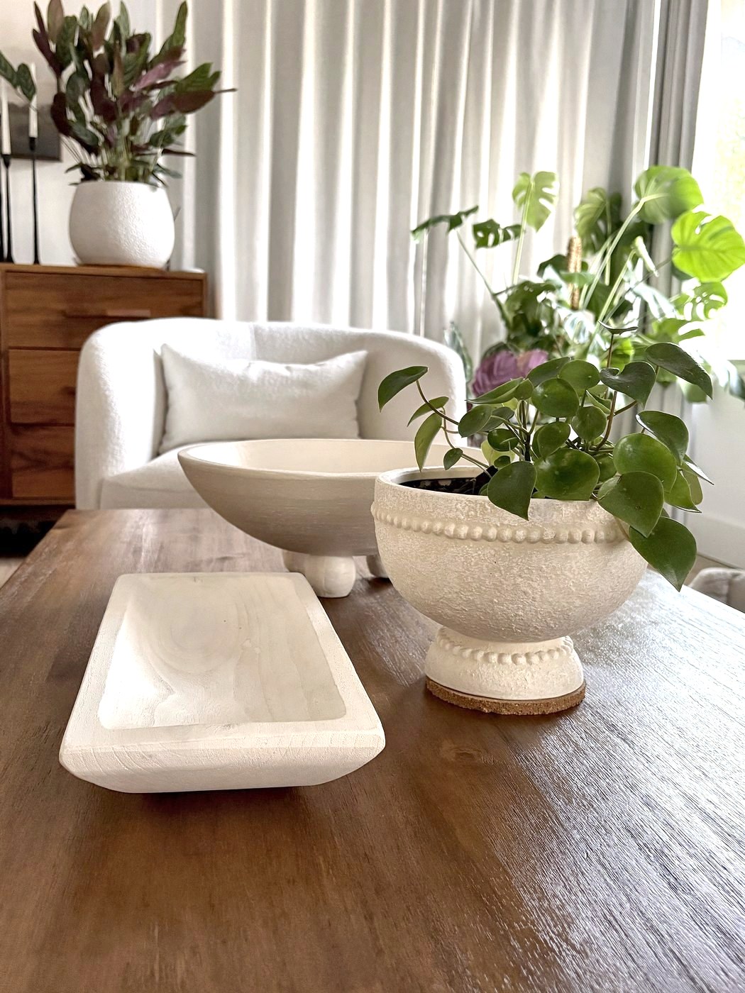 Coffee table styled with a whitewashed wood tray, footed bowl and a beaded planter with a pilea