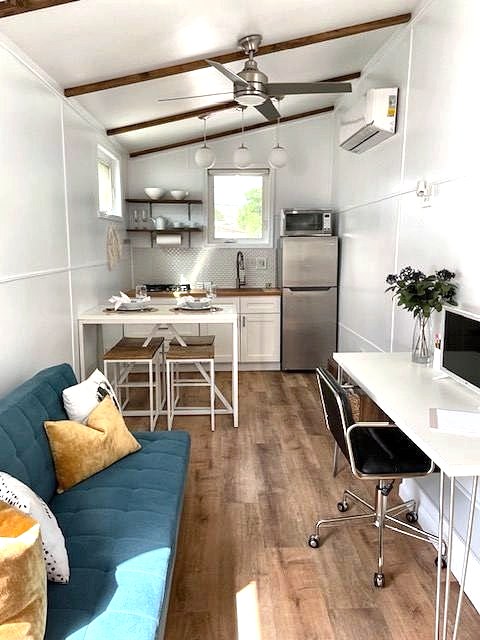 Tiny home interior with teal sofa, compact kitchen and desk nook