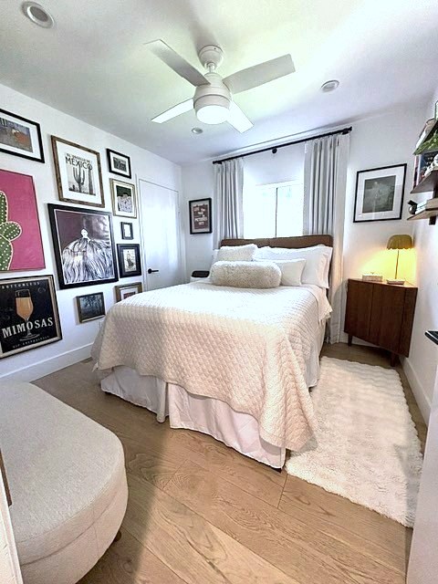 Guest bedroom with cream quilt and a colorful framed art wall