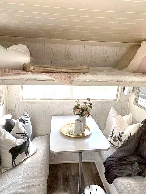 Vintage trailer dinette styled with pillows, flowers and a tray